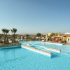 Piscina con palme e strutture residenziali sullo sfondo.